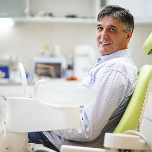 Male patient sitting in dental chair and smiling