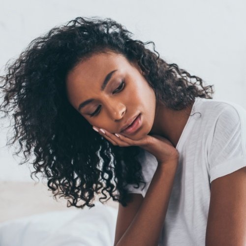 Woman in need of emergency dentistry holding cheek in pain