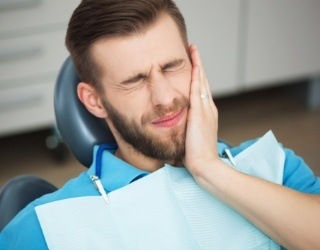 Man with jaw pain holding cheek