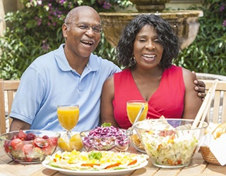 Man and woman with dental implants eating a meal