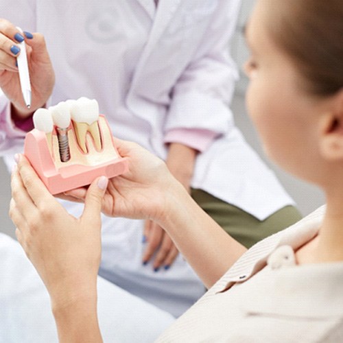 A dentist using an implant model to explain implants to a patient