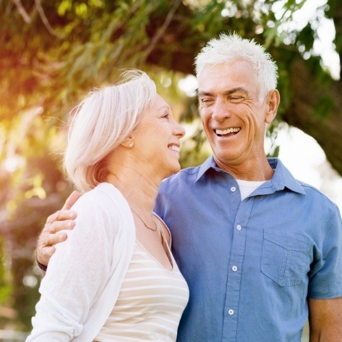 Man and woman smiling after dental bridge tooth replacement