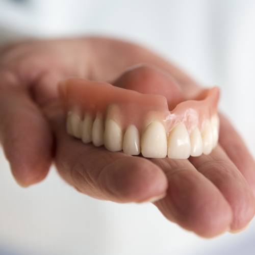 Hand holding a denture