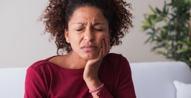 Woman in need of emergency dentistry holding cheek in pain