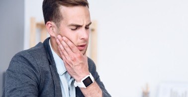 Man in need of T M J therapy holding jaw in pain