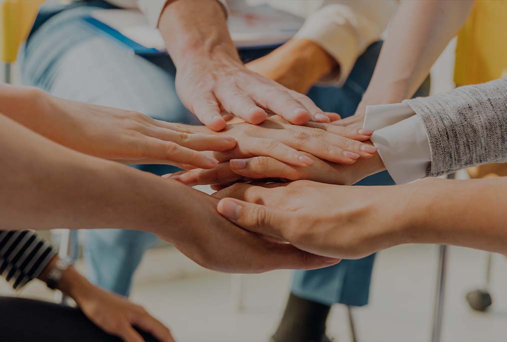 Group of people in a circle putting their hands together