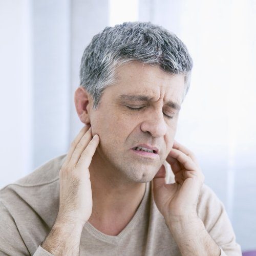 Man in need of T M J therapy holding jaw in pain